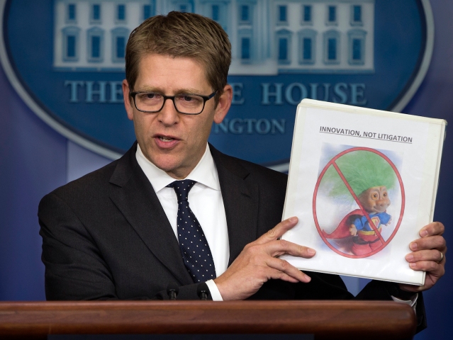 White House press secretary Jay Carney holds up a folder with an image of a troll and the words "innovation, not litigation" during the daily press briefing at the White House in Washington, Tuesday, June 4, 2013. Carney pointed out that the Obama administration is taking action to limit frivolous patent lawsuits, or "patent trolling." (AP Photo/Evan Vucci)
